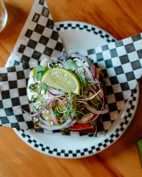 Avocado toast with fresh greens and lime on a checkerboard plate at Sociology